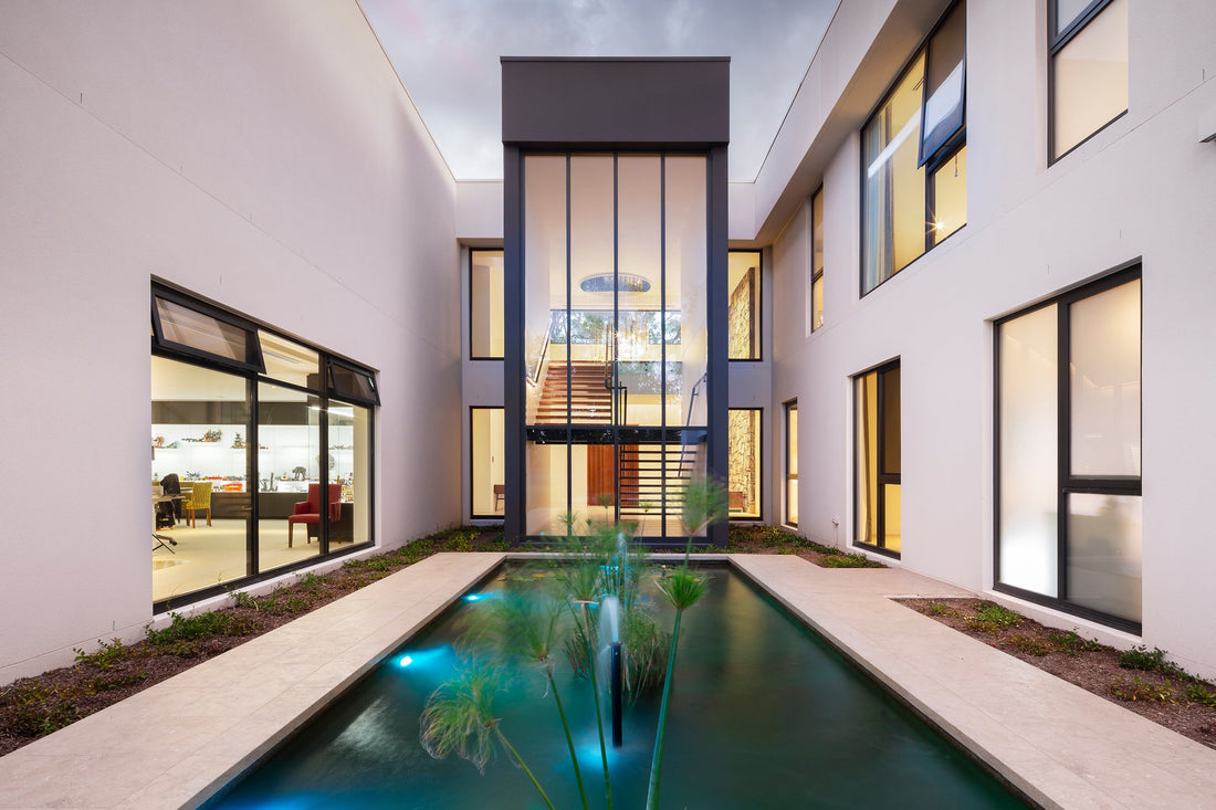 Courtyard and reflecting pool at dusk at the 2021 MBA House of the Year in Forrest, with interior and pool lighting on